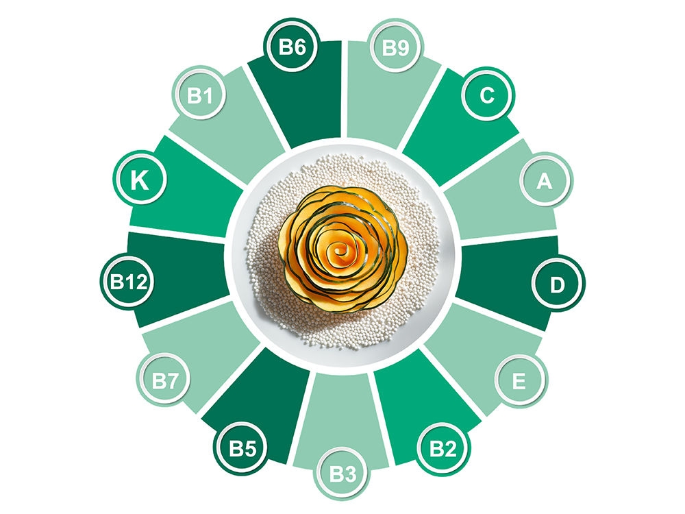 A pumpkin rose on a bed of puffed amaranth surrounded by a wheel of the 13 vitamin letters from A to K.