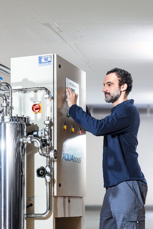 a man presses the button on the water device with the name "AquaBoss"