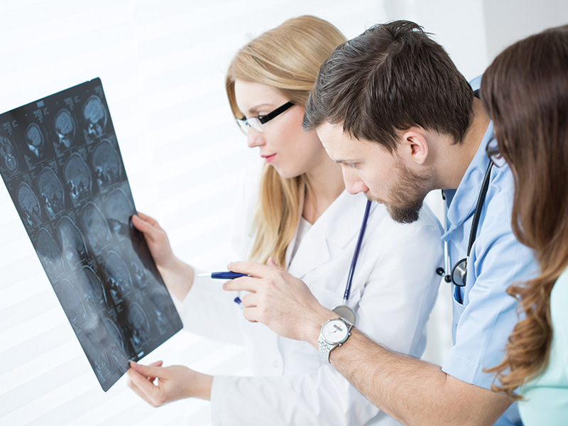 Three healthcare professionals analyzing a fluorography image, pointing out specific areas of interest